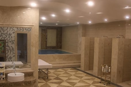 A hotel bathroom with a large bathtub, a sink, a mirror, and a tiled floor.. Lanyi Holiday Hotel