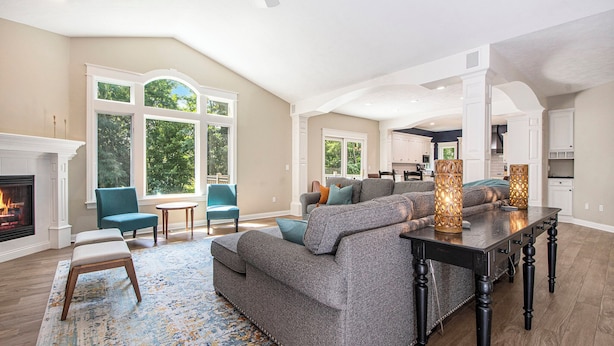 A spacious living room with a fireplace, large windows, a sofa, and a dining table.