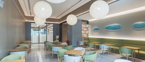 A modern interior with round chandeliers, green and blue seating, and a clean, polished floor.