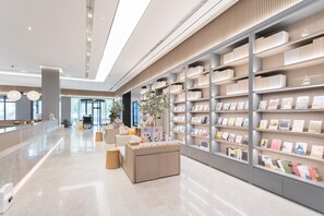 A modern library interior with bookshelves, a reception desk, and a clean, polished floor. - Ji Hotel (Korla)