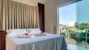 A hotel room with a large bed, a view of the outdoors, and a balcony with glass railings. - Casa na Praia de Tabuba por Carpediem (Caucaia)