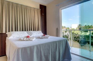 A hotel room with a large bed, a view of the outdoors, and a balcony with glass railings. - Casa na Praia de Tabuba por Carpediem (Caucaia)