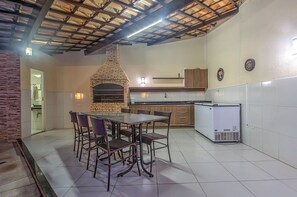Uma cozinha com forno de tijolos, azulejos brancos e armários de madeira.