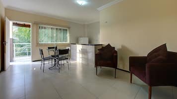 Un amplio espacio habitable con una mesa de comedor, dos sillas, un sofá y un refrigerador.