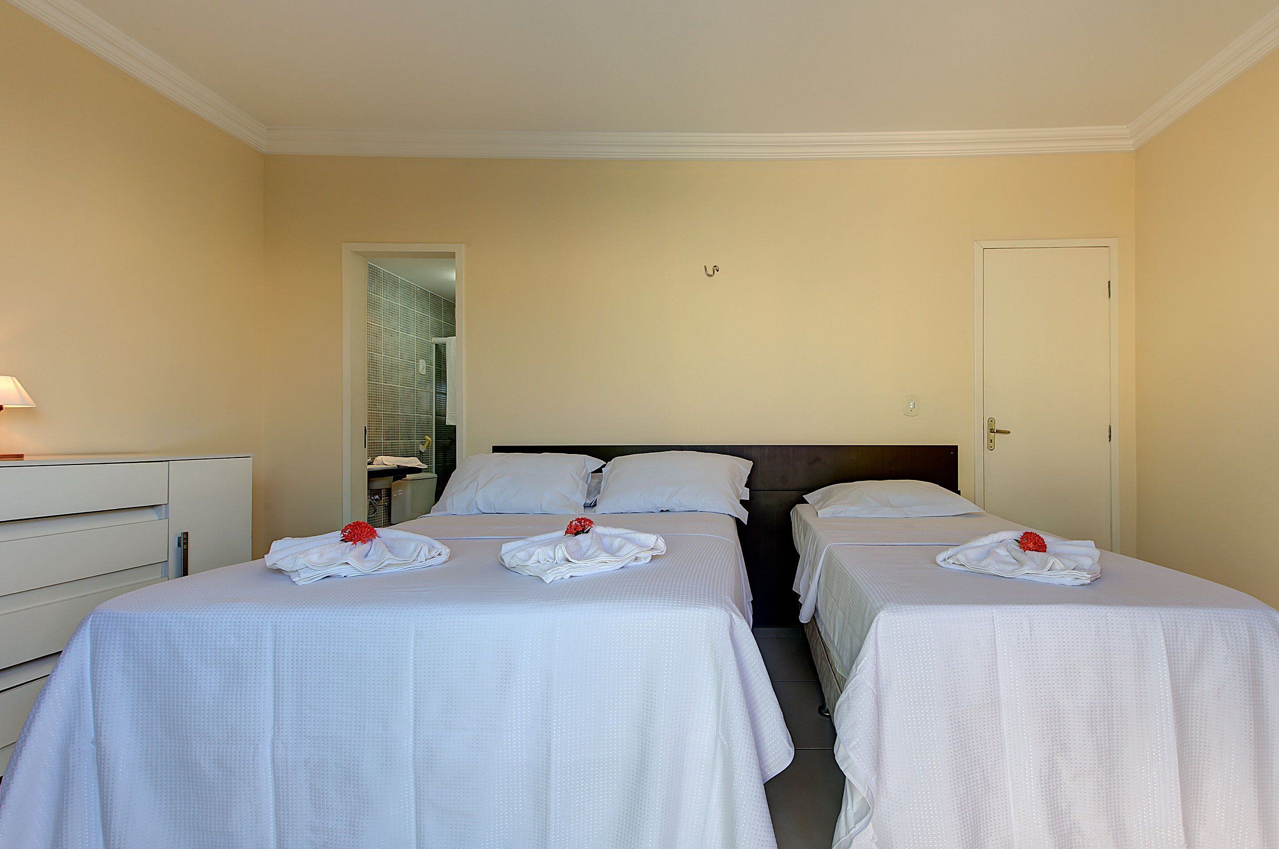 Habitación de hotel con dos camas, una mesita de noche y una puerta.