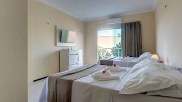 Una habitación de hotel con dos camas, un televisor, una ventana con cortinas y un balcón.