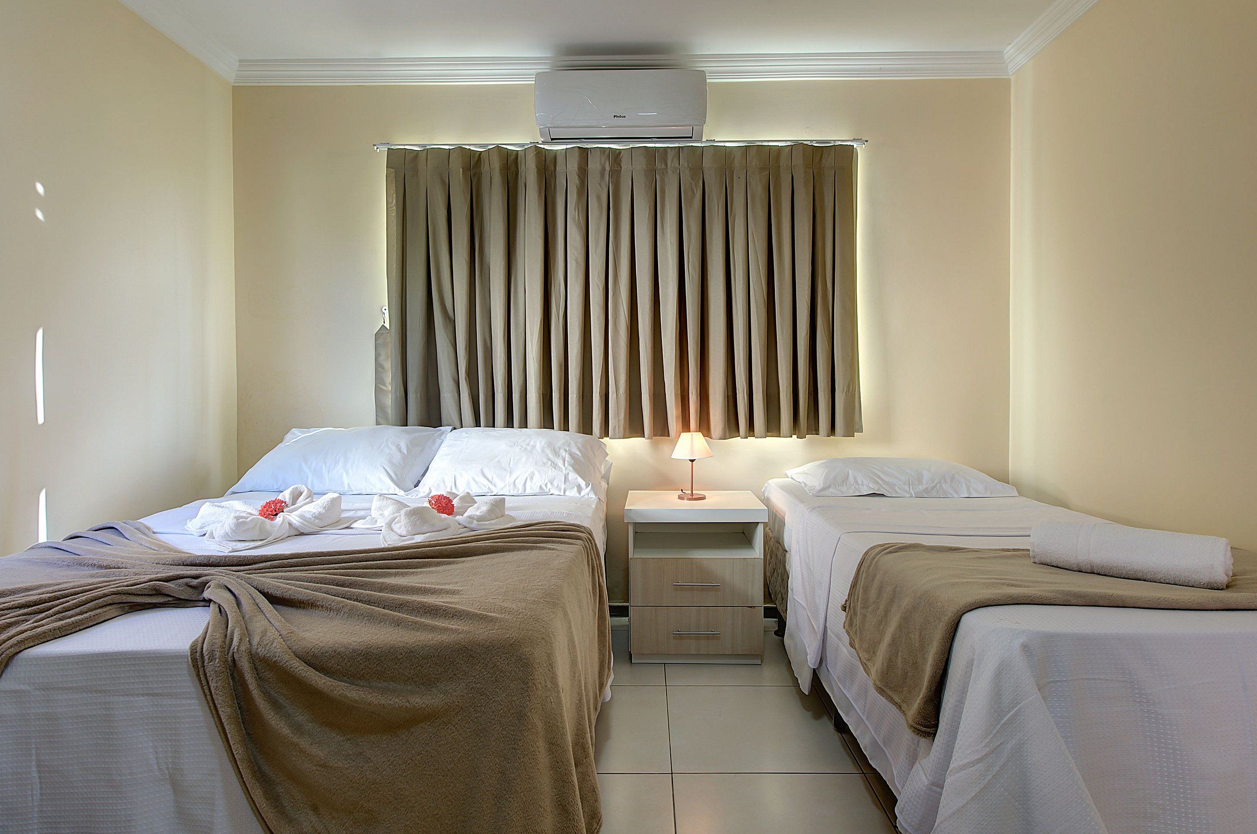 Une chambre d’hôtel avec deux lits, une table de chevet, une lampe et un appareil de climatisation.