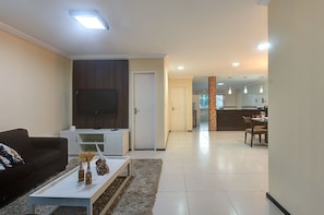 Uma sala de estar moderna com televisão de tela plana, um sofá e uma mesa de centro com objetos decorativos.