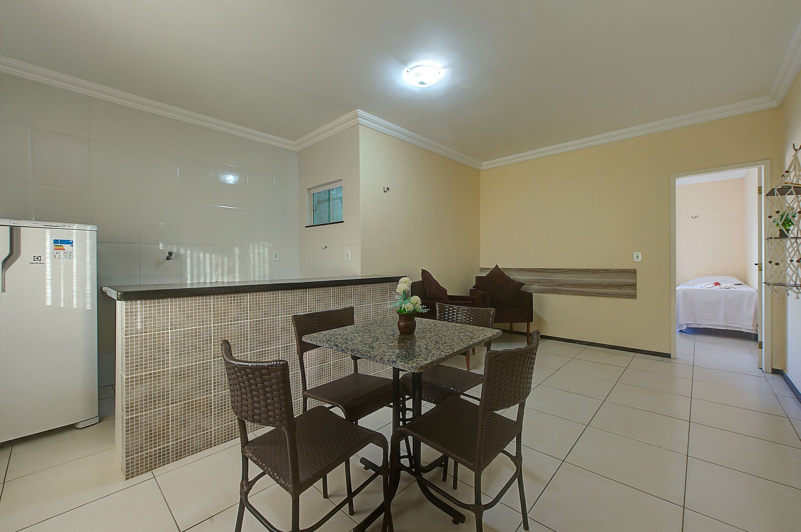 Un comedor con suelo de baldosas, una encimera de cocina y un refrigerador.