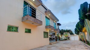 A modern two-story building with a spacious patio area, large windows, and a covered outdoor seating area. - Casa na Praia de Tabuba por Carpediem (Caucaia)