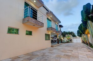 A modern two-story building with a spacious patio area, large windows, and a covered outdoor seating area. - Casa na Praia de Tabuba por Carpediem (Caucaia)
