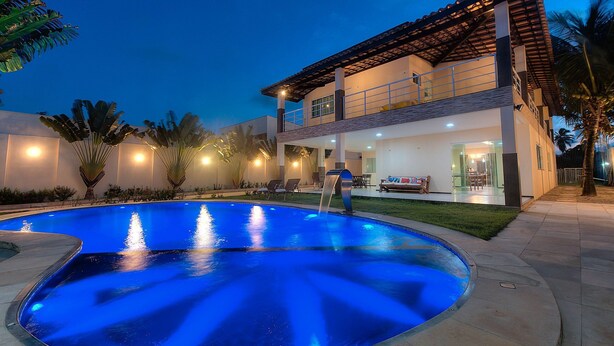 A modern two-story house with a swimming pool, outdoor seating, and a well-lit patio area. - Casa na Praia de Tabuba por Carpediem (Caucaia)
