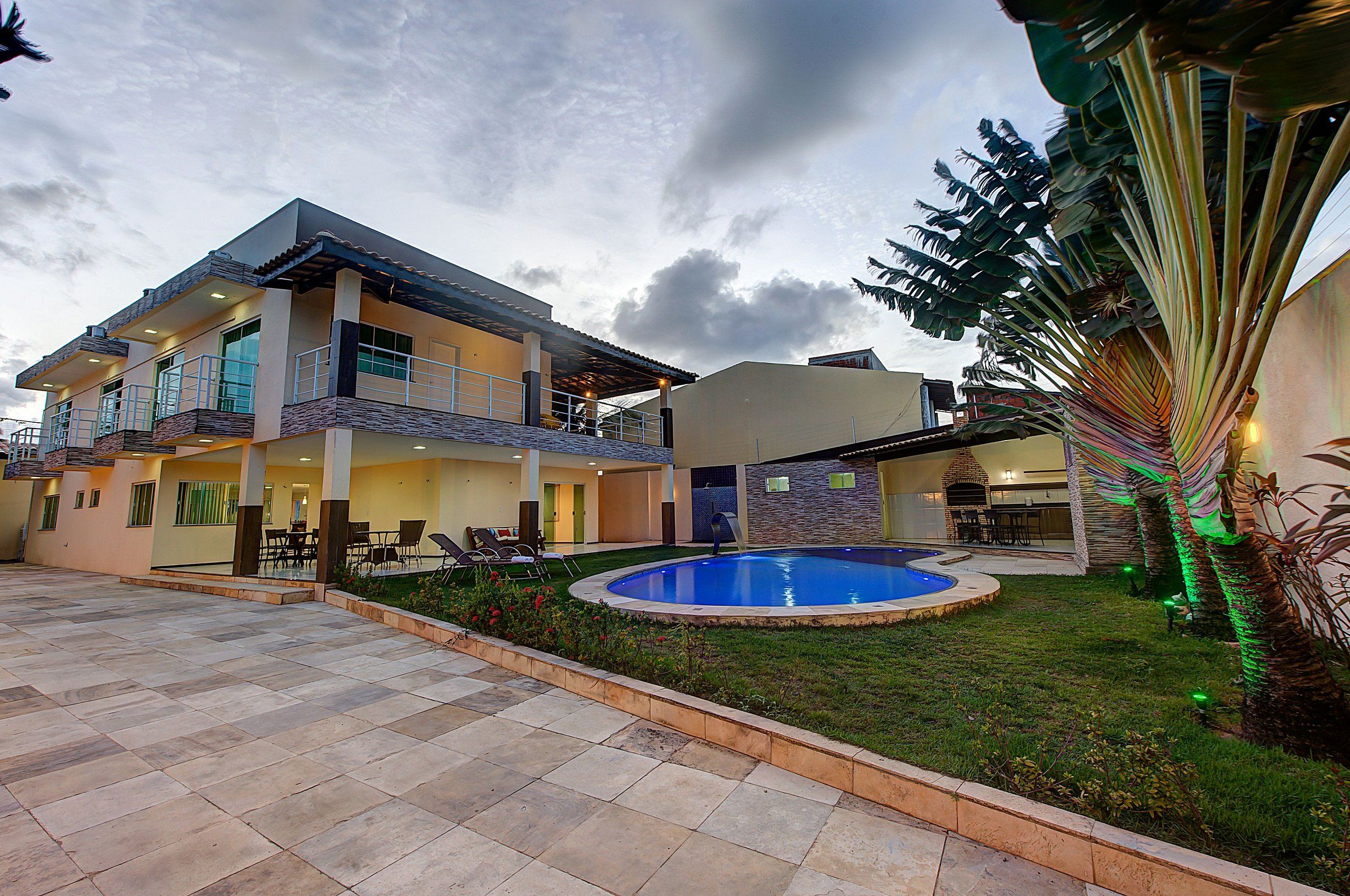 Una casa de dos plantas con piscina, mobiliario exterior y césped bien cuidado.