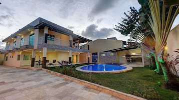 Una casa de dos plantas con piscina, mobiliario exterior y césped bien cuidado.