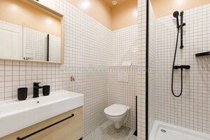 Moderni kylpyhuone, jossa on valkoinen pesuallas, peili ja wc-istuin.