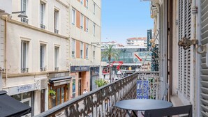 A balcony with a view of a city street, including a hotel named "HOTEL ESTEREL" and a restaurant named "LA MESSIE NUIE". - August-2523- (Cannes)