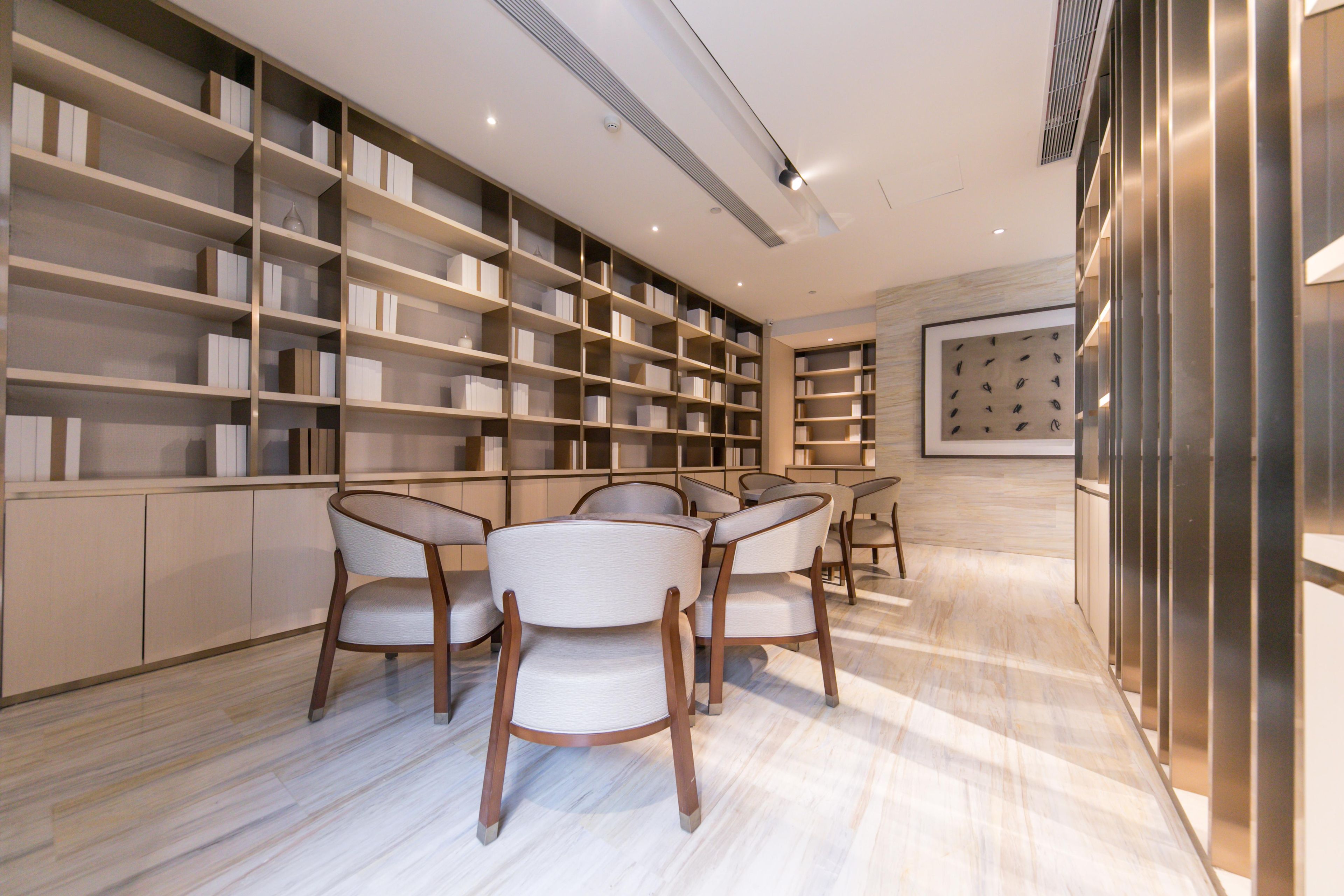 A modern interior with a marble floor, a bookshelf, and a dining area with chairs.