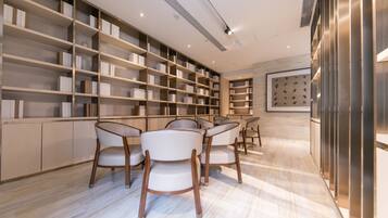 A modern interior with a marble floor, a bookshelf, and a dining area with chairs.