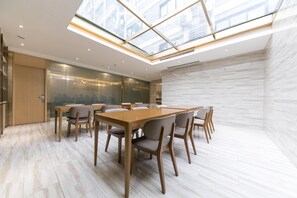 A modern meeting room with a glass ceiling, wooden tables, and chairs. - Ji Hotel (Tongchuan)