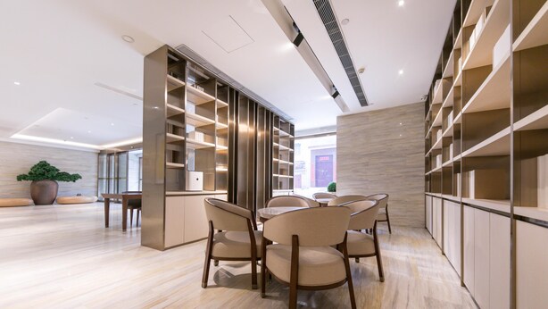 A modern interior with a dining area featuring a round table and chairs, built-in shelving, and a marble floor. - Ji Hotel (Tongchuan)