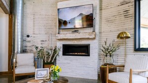 Ein gemütliches Wohnzimmer mit Kamin, Wandfernseher und bequemen Sitzmöglichkeiten.