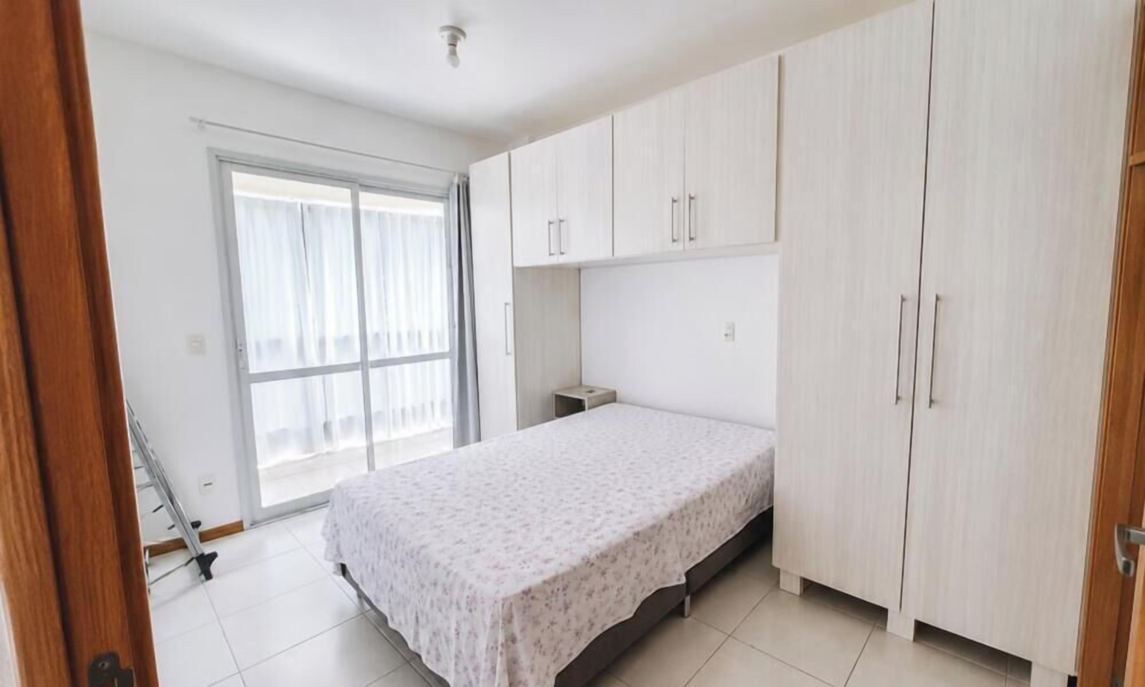 A bedroom with a bed, a wardrobe, a window, and a door.