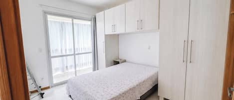 Un dormitorio con cama, armario, ventana y puerta.