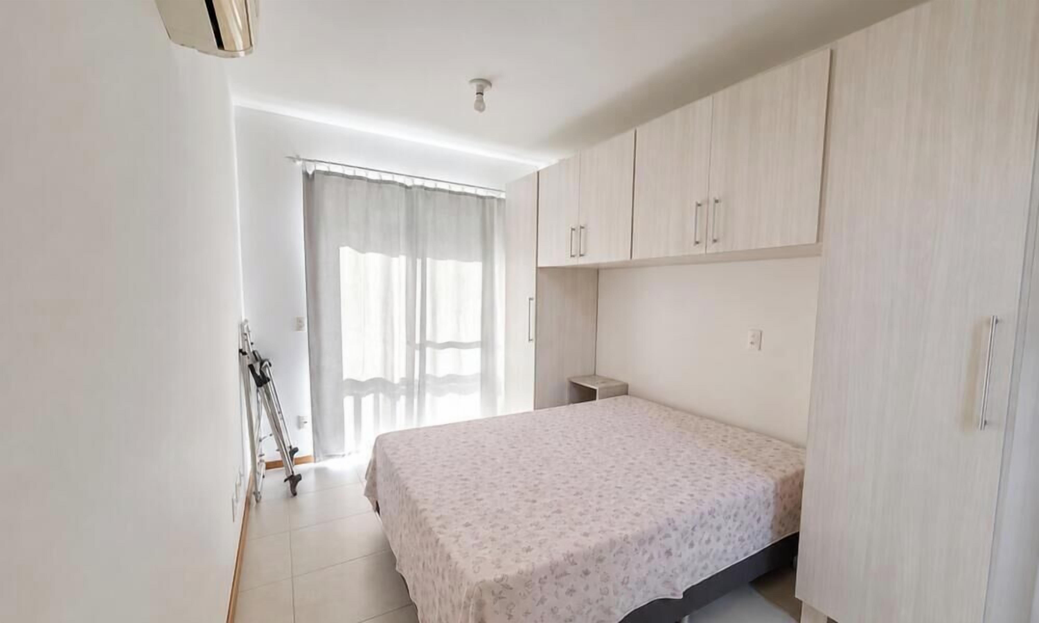 A bedroom with a bed, a wardrobe, and a window with curtains.