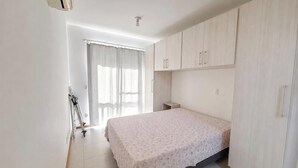 Un dormitorio con cama, armario y ventana con cortinas.