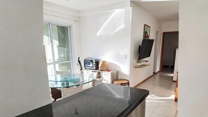 Una cocina moderna con una mesa de comedor de vidrio, horno empotrado y un televisor de pantalla plana sobre un soporte.