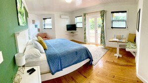 Un dormitorio con cama, mesita de noche, televisor y un escritorio pequeño con silla.