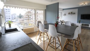 Une cuisine moderne dotée d’un grand îlot central, de chaises blanches et d’une table à manger.