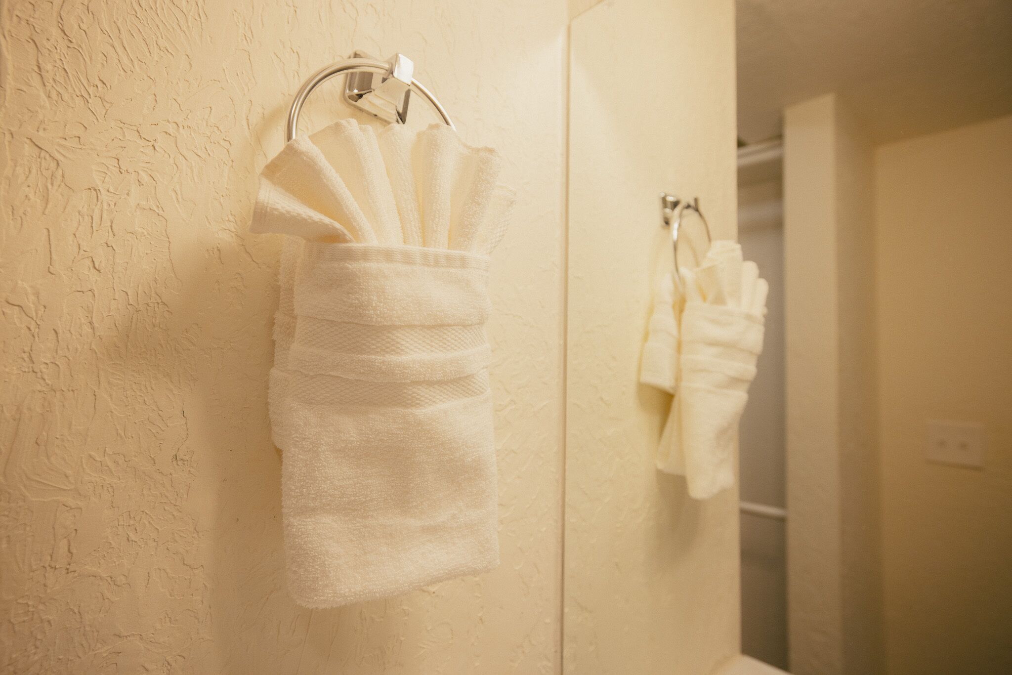 A bathroom with a towel rack holding several white towels.