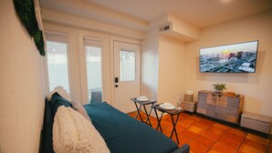 A room with a bed, a small table with a glass of wine, a television on the wall, and a cabinet.