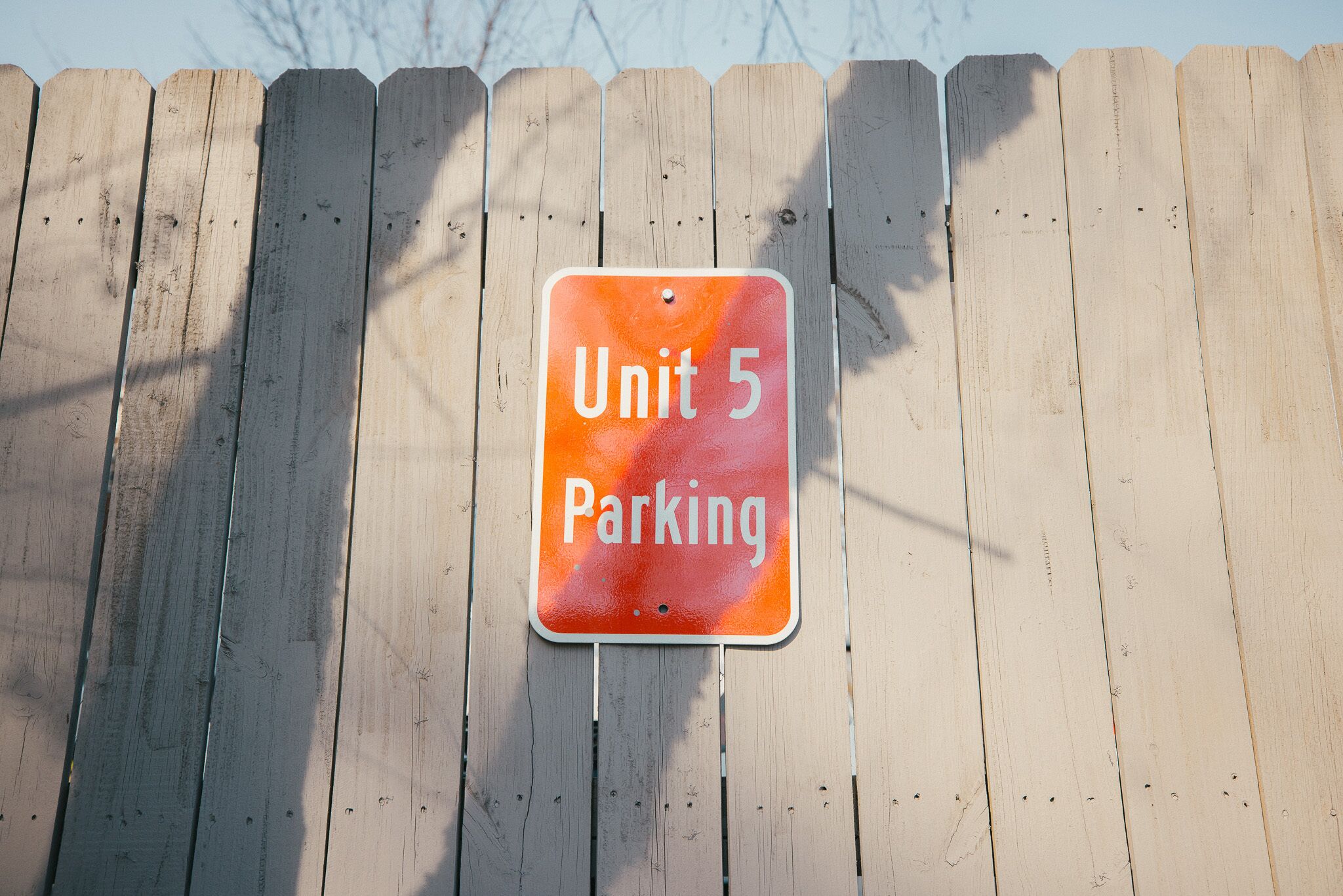 A wooden fence with a sign that reads "Unit 5 Parking".
