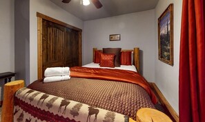 A bedroom with a wooden headboard, a bed with a patterned blanket, and a red curtain. - Creekside Cabin near Lake Coeur d'Alene | Pet-friendly retreat (Coeur d'Alene)