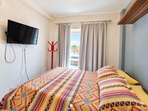 A hotel room with a bed, a television mounted on the wall, a window with curtains, and a view of the outside. - Nautilus Paradise in Penha-SC (Penha)