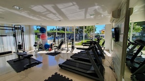 Uma academia com diversos equipamentos de exercício, incluindo esteiras, aparelhos de musculação e pesos livres.