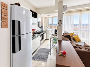 A modern kitchen with a refrigerator, stove, and dining area. - Nautilus Paradise in Penha-SC (Penha)