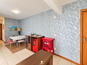 A compact living space with a dining area, kitchenette, and a red cabinet. - Nautilus Paradise in Penha-SC (Penha)