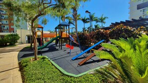 A playground with slides and climbing structures, surrounded by greenery and buildings. - Nautilus Paradise in Penha-SC (Penha)