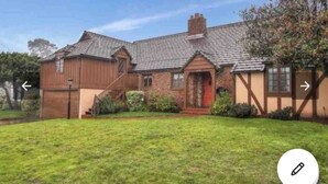 A two-story house with a sloped roof, a front porch, and a well-maintained lawn. - A totally separated beautiful golf⛳️course view small  house in the back yard  (Daly City)