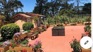 A small building with a red roof, surrounded by flower beds and a paved patio area. - A totally separated beautiful golf⛳️course view small  house in the back yard  (Daly City)