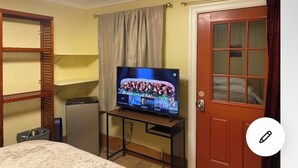 A room with a bed, a TV on a stand, a small fridge, and a door with a window. - A totally separated beautiful golf⛳️course view small  house in the back yard  (Daly City)