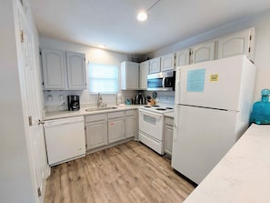 Kitchen features a sink, stove, refrigerator, and coffee maker.