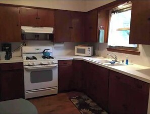 A compact kitchen with a stove, microwave, and sink.