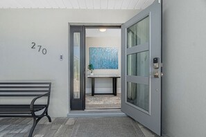 Un ingresso moderno con una panchina, una porta con un pannello in vetro e il numero '270' apposto al muro.