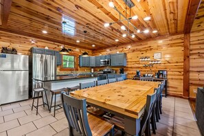 Een moderne keuken met houten wanden, roestvrijstalen apparatuur en een centraal eiland met zitplaatsen.