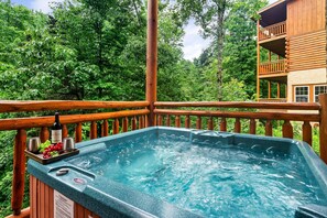Een hottub op een houten terras, met een houten gebouw op de achtergrond.