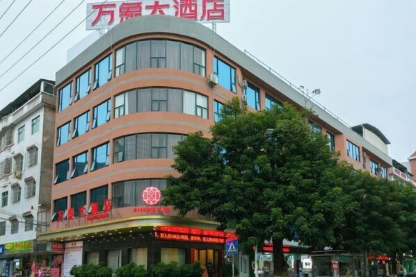 A multi-story hotel with a curved facade, large windows, and a prominent red sign at the top.